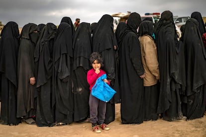 Um grupo de mulheres com véus se alinha em um posto de controle das Forças Democráticas da Síria - a aliança de milícias curdas-árabes apoiadas pelos Estados Unidos - em 5 de março fora de Baghuz, o último enclave na Síria controlado pelo Estado Islâmico