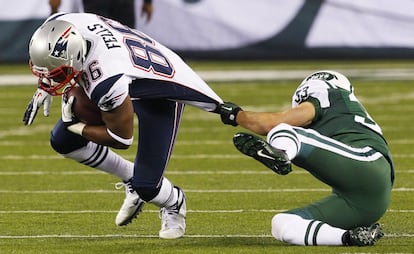 Eric Smith, de los New York Jets, agarra de la camiesta a Daniel Fells, de los New England Patriots, en un partido de la Liga estadounidense de f&uacute;tbol americano.
