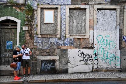 Dos turistas paseando por el centro de Lisboa.Muchas fachadas han perdido la belleza y quedan ahora repletas de huecos dejados por las piezas robadas para ser vendidas.