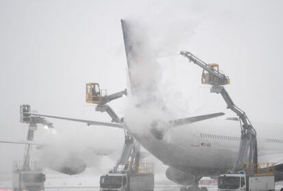 Varios operarios del aeropuerto de Frankfurt am Main (Alemania) trabajan para eliminar el hielo que cubre un Airbus A380-800 de la compañía Lufthansa.