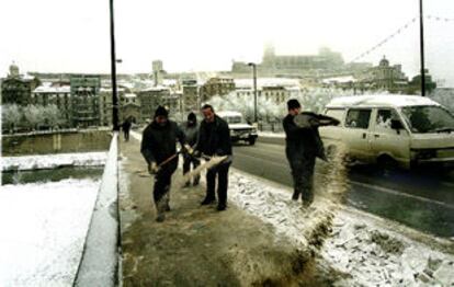 Operarios municipales tiran sal en la calzada, ayer, en el puente viejo de Lleida.