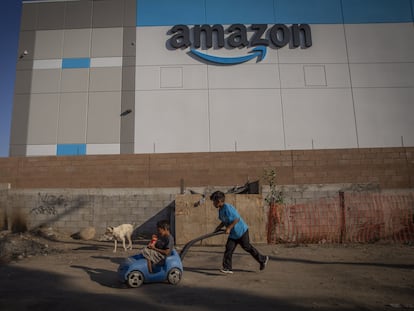 Dos niños juegan junto a la barda que separa un centro de distribución de Amazon y la colonia Cañón del Padre, en Tijuana, en una imagen de archivo.