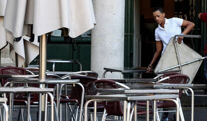 Un trabajador coloca mesas de una terraza.