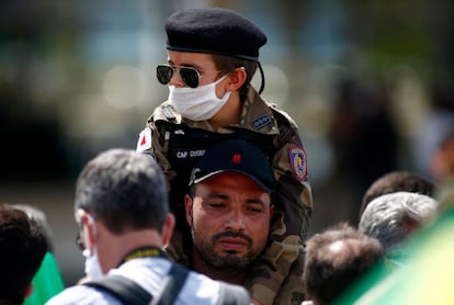 Apoiador de Bolsonaro segura menino com traje militar nos ombros durante uma manifestação em Brasília, em 17 de maio de 2020.