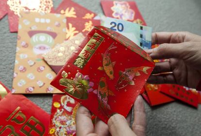 Una mujer mete un billete en un 'sobre de la suerte' durante el tercer día del Nuevo Año Chino, en Hong Kong (China).