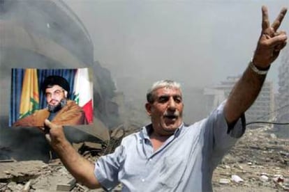 Un militante de Hezbolá muestra una foto del jeque Nasralá en una zona bombardeada del sur de Beirut.