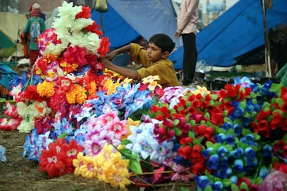 Un niño prepara ramos de flores artificiales durante la feria anual de granjeros en Shama Chak Jhiri (India).