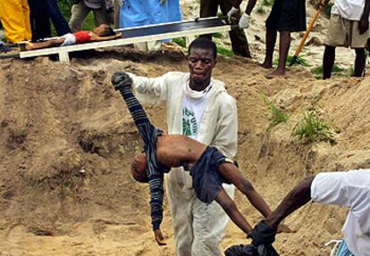 Un voluntario ayuda a enterrar a 66 civiles en una fosa común a las afueras  de Monrovia.