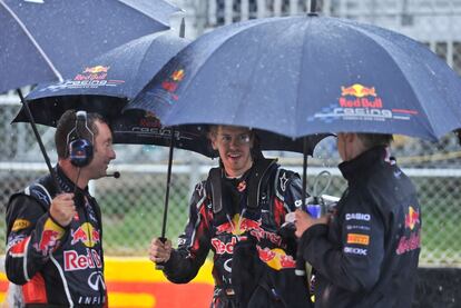 El piloto alemán charla con dos miembros de Red Bull durante la interrupción de la carrera.