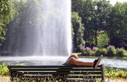 Un joven descansa tirado en un banco de un parque de Toulouse (Pars).