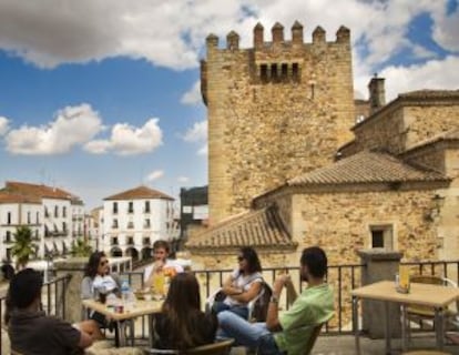Un grupo de jóvenes en una terraza de verano, junto a la Torre de Bujaco (Cáceres).