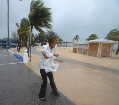 Una mujer camina en medio de un fuerte viento en Key West, Florida . Fuertes vientos y lluvias torrenciales anticiparon hoy el paso de la fortalecida tormenta tropical Isaac cerca del sur de Florida, que permanece en estado de emergencia.