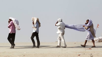 Unos hombres se abren paso en la orilla del río Ganges durante una tormenta de polvo en Allahabad (India).