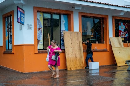 La velocidad de los vientos de 'Lidia' ha aumentado 112 km/h en las últimas 24 horas. En la imagen, una mujer camina por el centro de Puerto Vallarta (Estado de Jalisco), mientras un hombre trabaja para proteger un local comercial de los daños que pueda sufrir durante la tormenta.