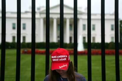 Una turista luce la gorra de béisbol roja emblema de los simpatizantes de Donald Trump frente a la Casa Blanca