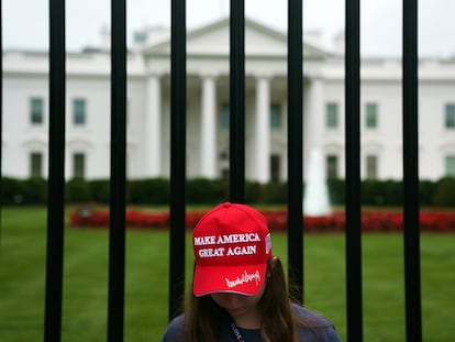 Una turista luce la gorra de béisbol roja emblema de los simpatizantes de Donald Trump frente a la Casa Blanca