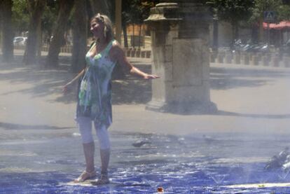 Una mujer se refresca con el agua salida de los aspersores de la Alameda de Hércules (Sevilla).