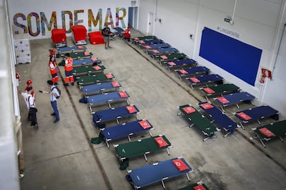 Efectivos de Cruz Roja preparan camas en uno de los pabellones del puerto de Valencia para acoger a los migrantes. 
