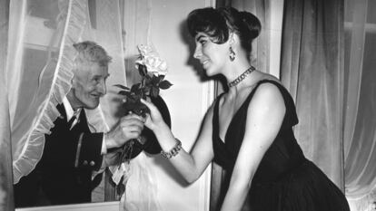 La actriz británica Joan Collins en Londres, en 1955, recibiendo flores de un viejo admirador en su apartamento.