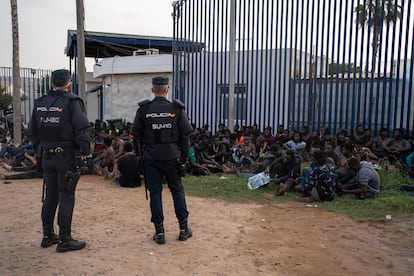 Agentes de la Policía Nacional junto al grupo de inmigrantes en las puertas del CETI de Melilla.