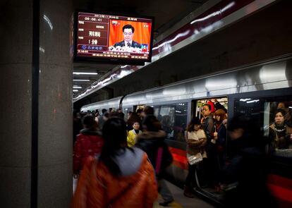 Pasajeros en una estación de metro de Pekín pasan ante un televisor que muestra la retransmisión en directo del discurso de apertura del presidente chino. Hu Jintao advirtió de que si el Partido Comunista no lucha contra la corrupción afrontará "su caída y la del Estado".