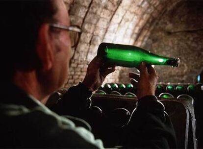 Un trabajador observa al trasluz una botella de cava.