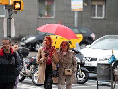 Varias personas con paraguas pasean por Barcelona este viernes.