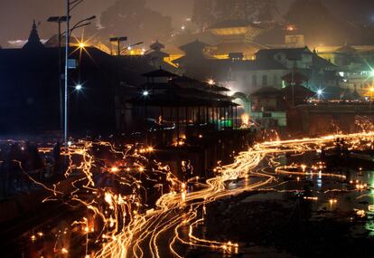 Los devotos nepaleses lanzan lámparas de aceite en memoria de miembros de la familia fallecidos durante el festival Balachaturdashi en el templo Pashupati en Katmandú (Nepal).