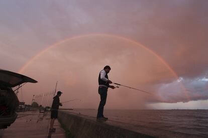 Dos hombres pescan bajo un arcoíris en el puerto de Portsmouth, en Kingston (Ontario).