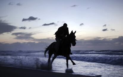 Un hombre palestino monta a caballo en una playa al atarceder, en Gaza.