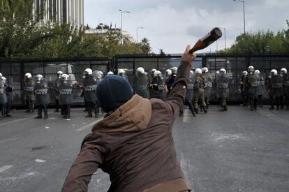 Un manifestante lanza una botella contra los policías antidisturbios.