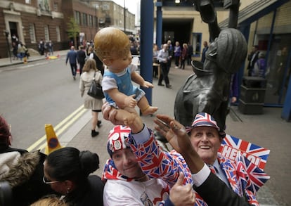 John Loughrey and Terry Hutt (d) alzan un muñeco de un bebe con una corona tras conocer el anuncio del nacimiento del nuevo príncipe de Cambridge frente al hospital St Mary de Londres.
