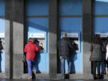 Varias personas en los cajeros de una oficina de Novagalicia, esta mañana en Santiago de Compostela.