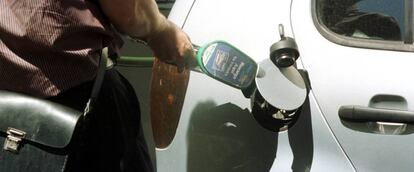 Trabajador de una estación de servico poniendo gasolina a un coche.