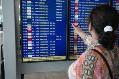 Una passatgera consulta una pantalla informativa a l'aeroport del Prat.