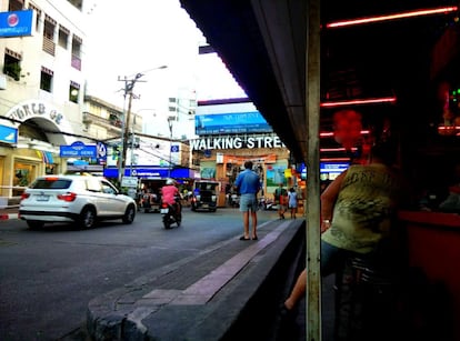 Al fondo, la puerta de entrada a la calle peatonal de Pattaya da acceso a uno de los mayores focos de turismo sexual del mundo. Está a 150 kilómetros al sur de Bangkok, la capital de Tailandia, uno de los puntos calientes de la trata de personas en el mundo. Todavía es de día y la actividad no está a pleno rendimiento, pero ya hay bares, como el de la derecha, donde los clientes pueden alternar con chicas que están esperándoles para prestar servicios sexuales.