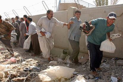 Varios iraquíes llevan bolsas con armas para entregarlas a cambio de dinero en el estadio de Ciudad Sáder, el principal barrio chií de Bagdad.