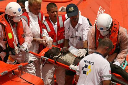 Voluntarios de la Cruz Roja atienden a uno de los inmigrantes heridos en el puerto de Los Cristianos.
