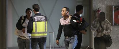 Un polic&iacute;a con viajeros llegados al aeropuerto de Barajas. 