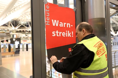 An airport security union representative posts a poster reading "Warning strike!" in an empty Terminal 2 at Hamburg Airport