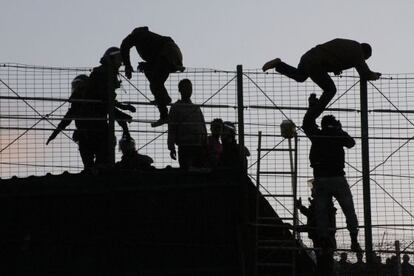 Inmigrantes subsaharianos saltando la valla de Melilla en presencia de agentes de la Guardia Civil el pasado mes de mayo.