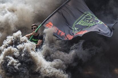 Un manifestante cubierto por el humo de las bengalas. 