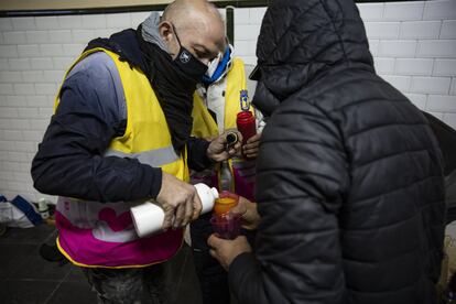 Un voluntario del Ayuntamiento de Madrid sirve caldo caliente a una persona sin techo.