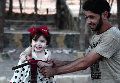 Un hombre juega con una niña en el segundo día del 'Eid el-Adha' o fiesta del sacrificio, la mayor festividad de la comunidad musulmana, en un parque de la ciudad siria de Afrin, el 22 de agosto de 2018. Desplazadas de sus hogares en la Ghouta Oriental de Siria, las familias buscaron refugio en casas abandonadas en la ciudad kurda de Afrin a principios de este año.