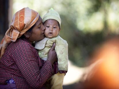 Una mujer besa a su bebé en la puerta de su vivienda, en una zona rural en Sindhupalchowk, Nepal.