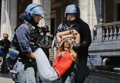 Una manifestante es arrastrada por la policía italiana frente al Ministerio de Transporte, en Roma. Decenas de manifestantes se encadenaron a los pasos en una manifestación contra la política de inmigración del gobierno.