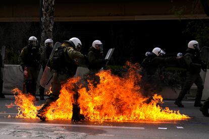 Las llamas de los 'cócteles molotov' lanzados por los manifestantes rodean a un grupo de agentes de la policía antidisturbios, durante la huelga general en Atenas este jueves.  