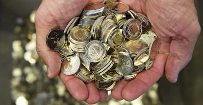 Un hombre sostiene varias monedas de euro. 
