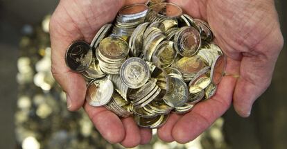 Un hombre sostiene varias monedas de euro.