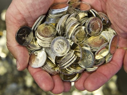 Un hombre sostiene varias monedas de euro. 